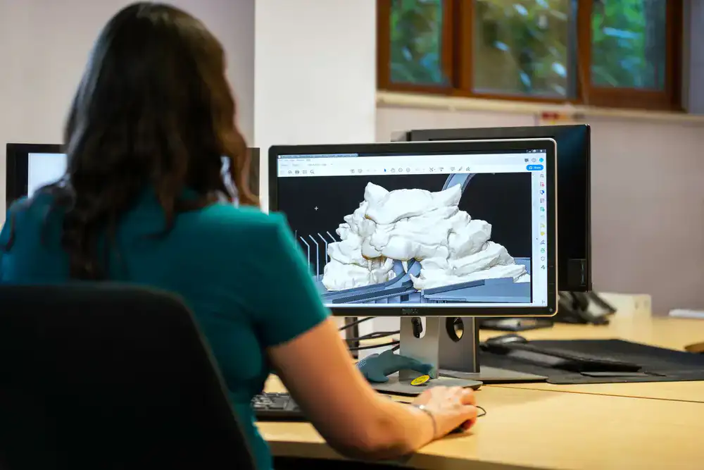 Technical artist reviewing a 3D model wireframe on a multi-monitor workstation